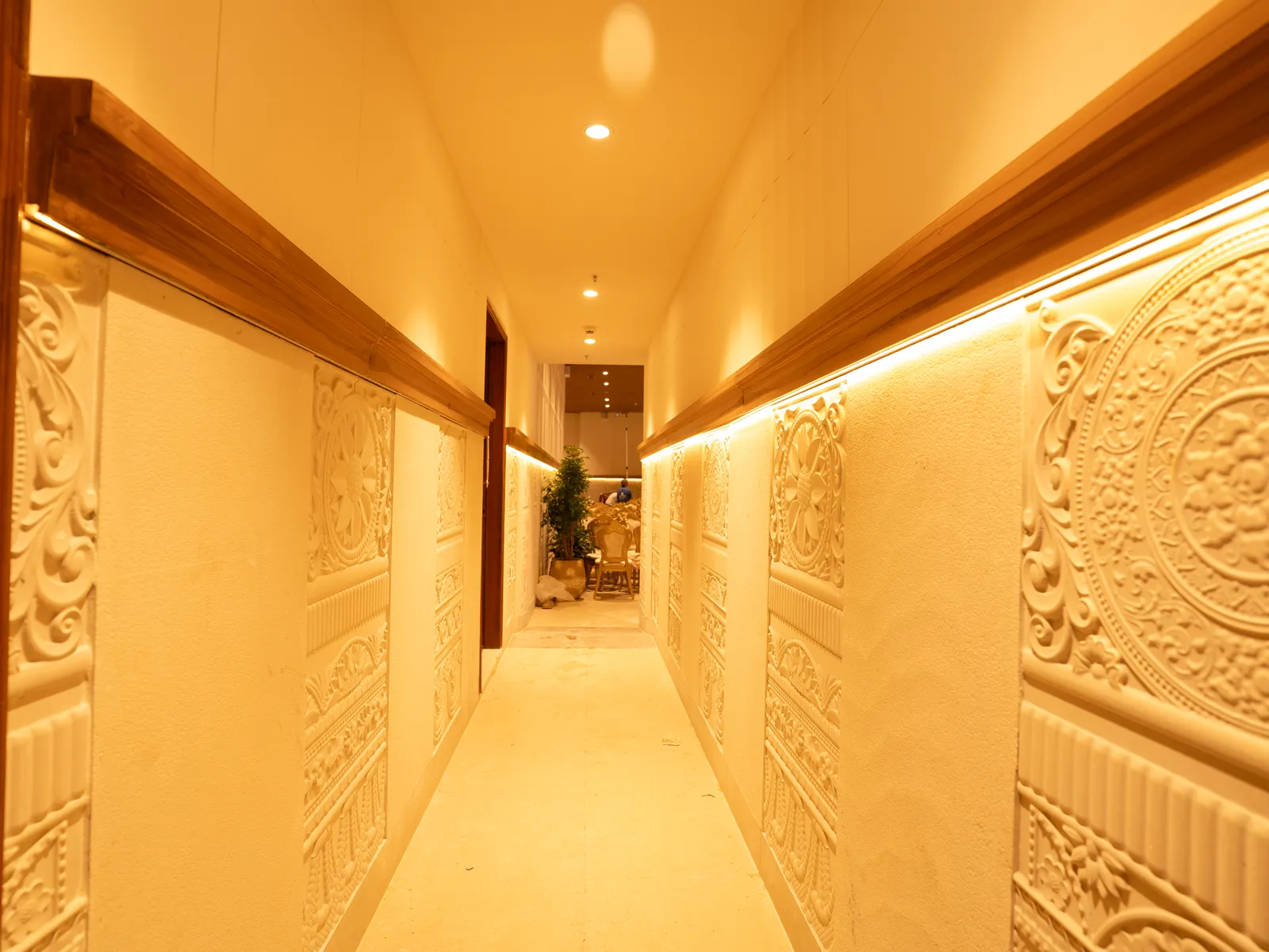 Corridor with carved wall panels and warm cove lighting — Chalukya Samrat